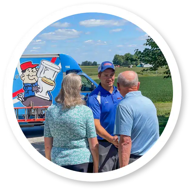 A Man In A Blue Uniform Shakes Hands With An Older Man Outdoors, While An Older Woman Stands Beside Them. In The Background, A Colorful Truck With Cartoon Graphics, Reminiscent Of A Gibson Painting, Adds A Whimsical Charm To The Scene.